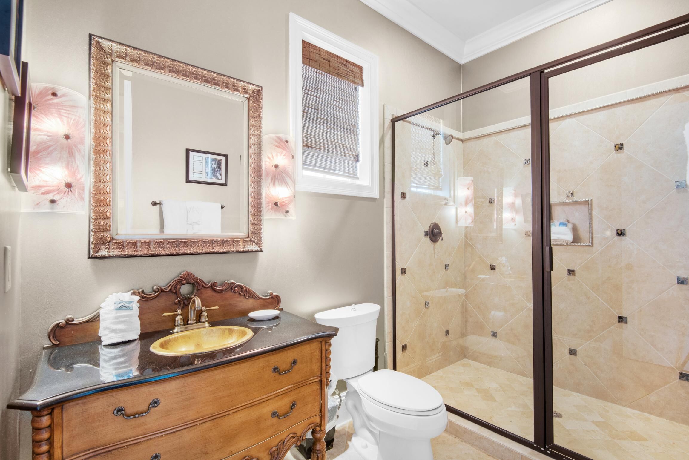 A bathroom with a wooden vanity, a large mirror, a toilet, and a glass-enclosed shower.