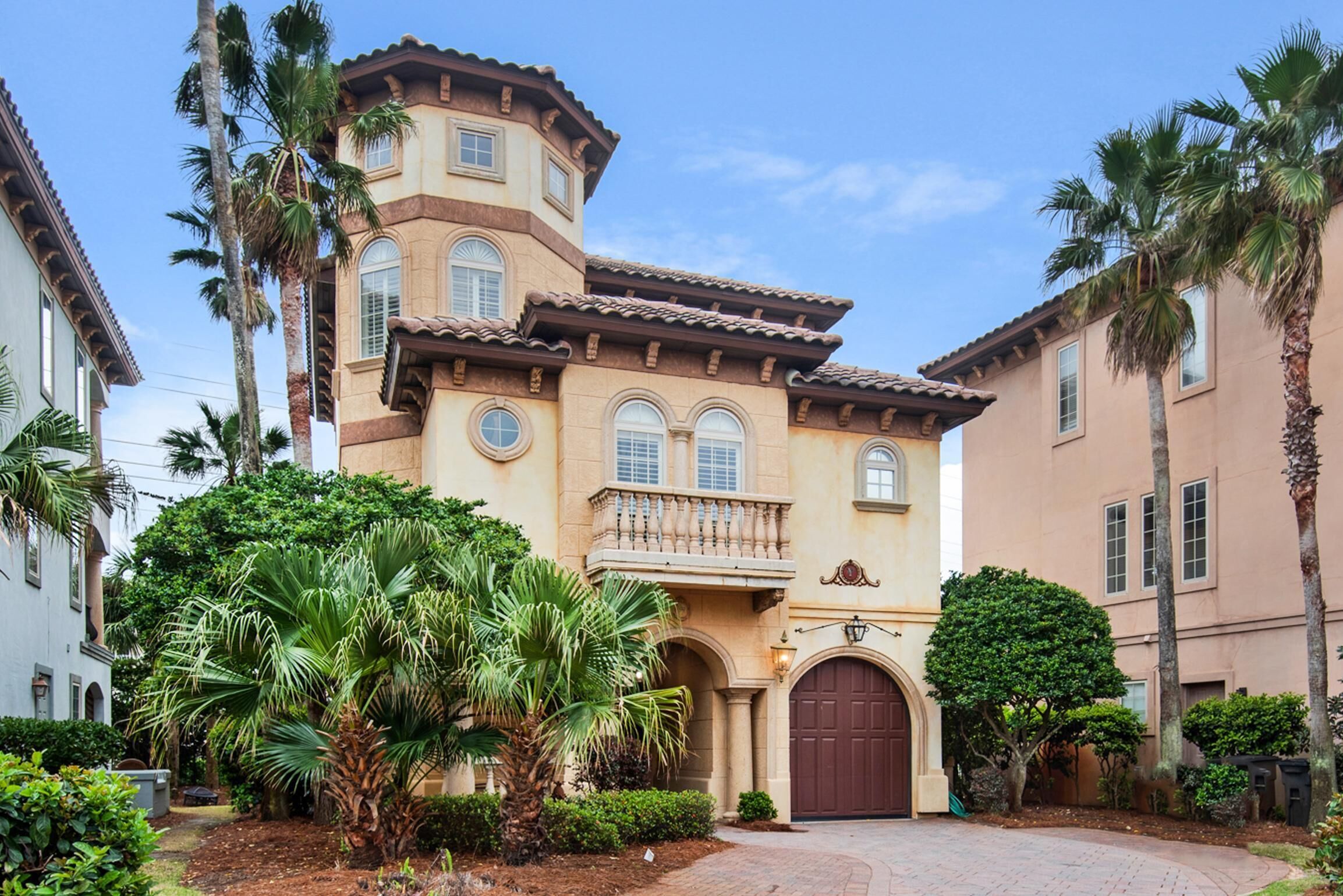 A Mediterranean-style building with a central courtyard, palm trees, and a brick pathway.