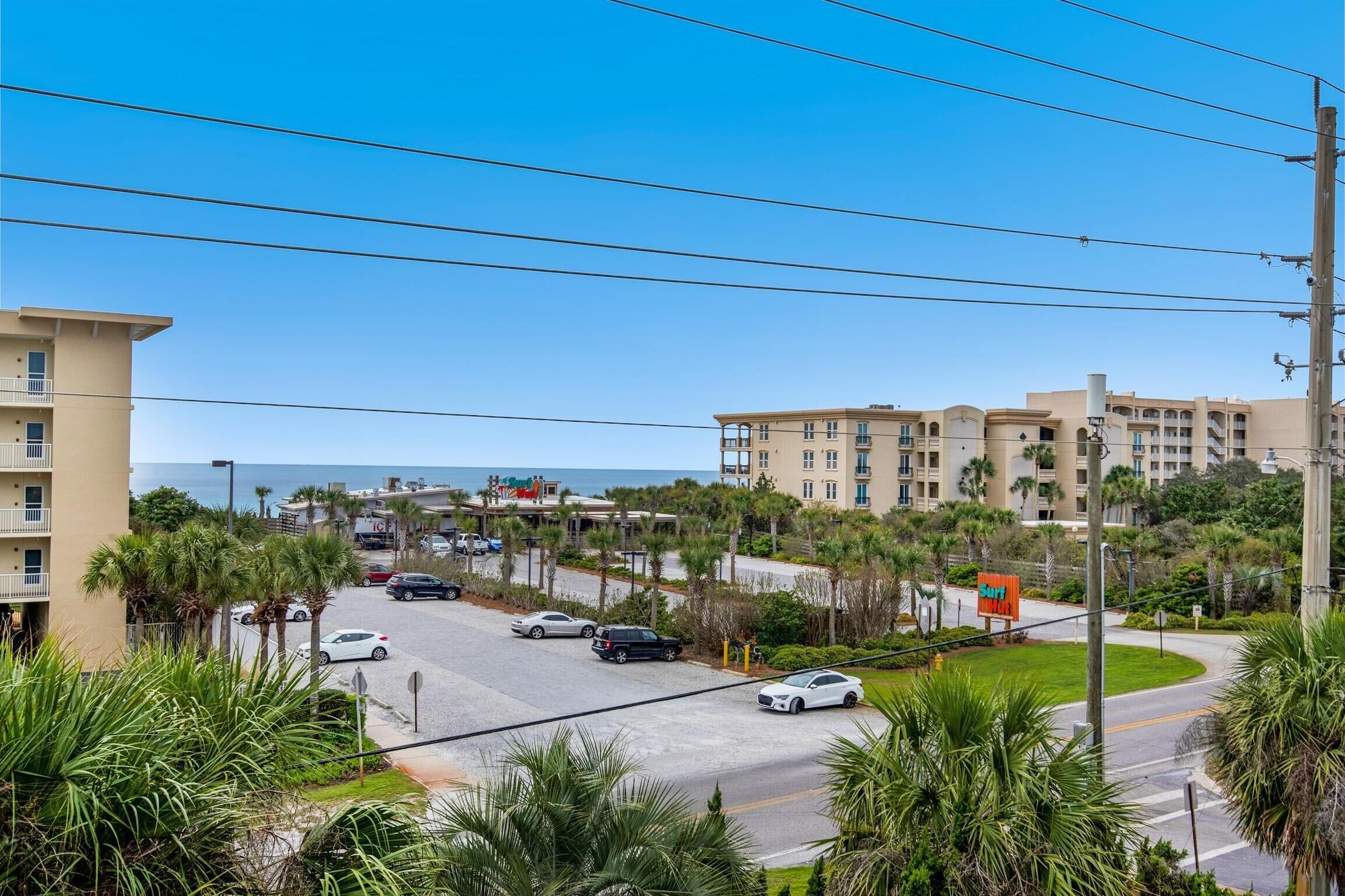Un hotel sulla costa con diversi piani, palme e vista sull'oceano.
