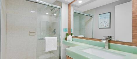 A modern bathroom with a glass-enclosed shower, a white toilet, and a green sink with a wooden vanity.