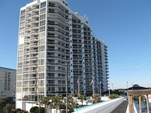 A multi-story hotel with balconies, a pool area, and a clear sky. - Surfside Resort #503 (Miramar Beach)