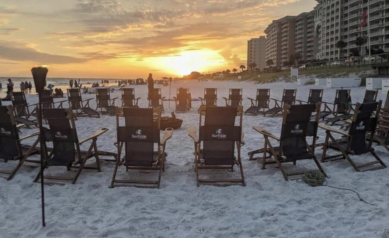Ein Strand mit Reihen leerer Liegen und einem Sonnenuntergang im Hintergrund.