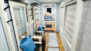 A narrow hallway with a bed, a desk, and a chair. - Marina’s Cozy Cottage. Family friendly with cold AC in summer and warm winters! (Rio Hondo)