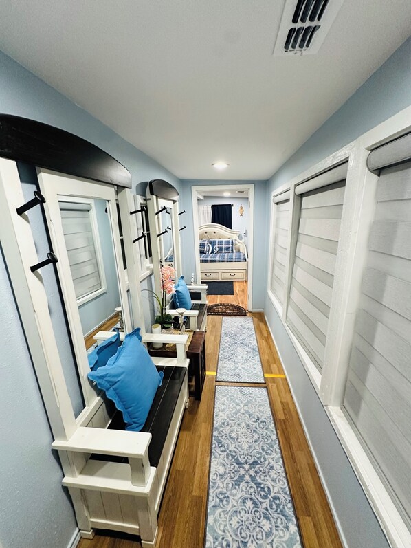 A narrow hallway with a bed, a desk, and a chair.