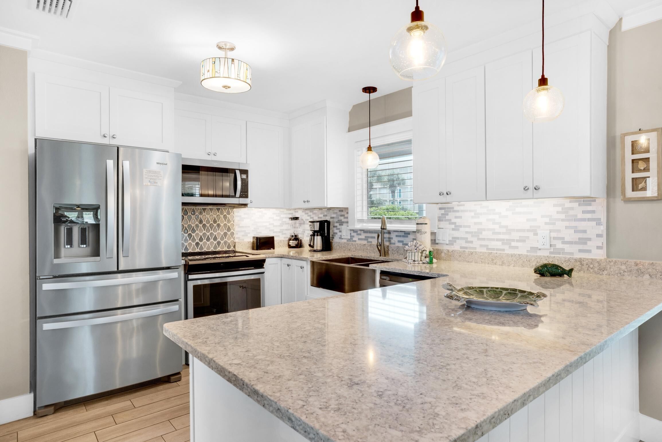 A modern kitchen with white cabinetry, stainless steel appliances, and a granite countertop.