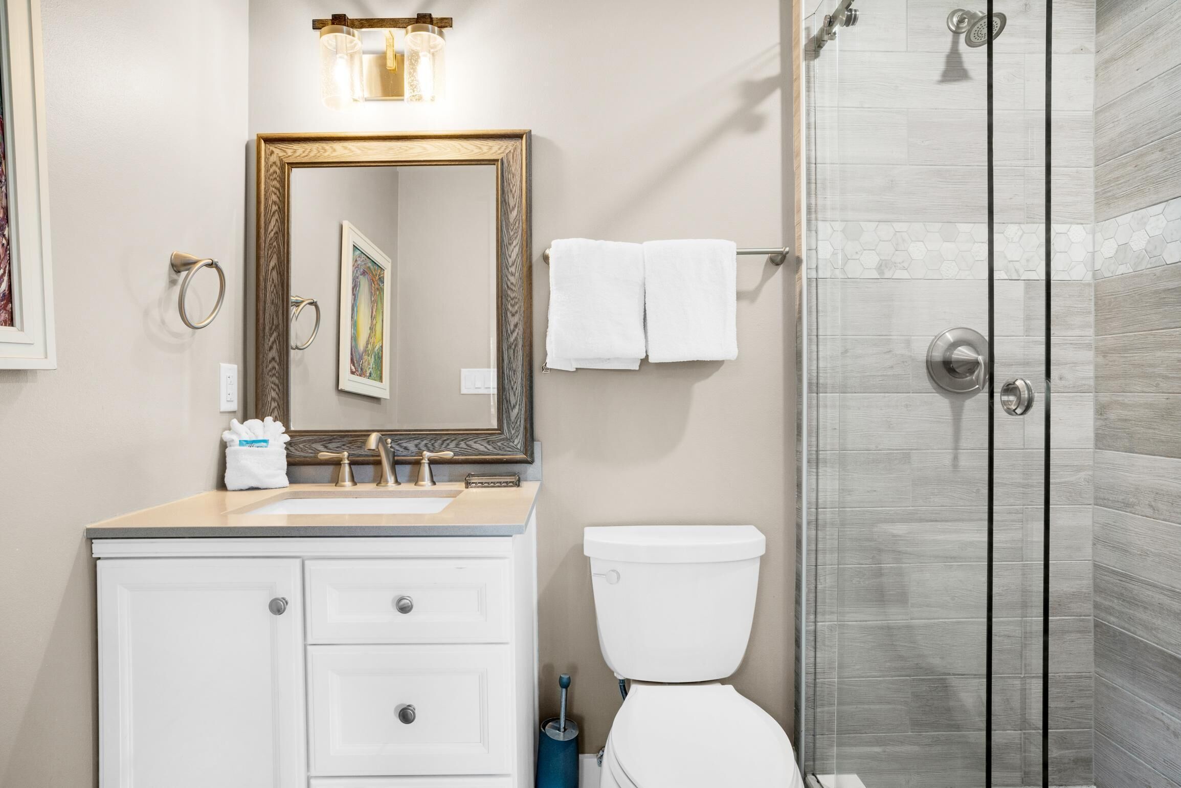 Ein Badezimmer mit Waschbecken, Spiegel, Toilette und Dusche.