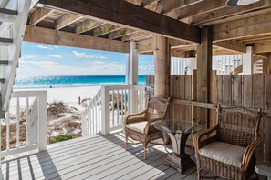 A wooden deck with wicker chairs and a glass table overlooking a beach. - Summer Haven A (Miramar Beach)