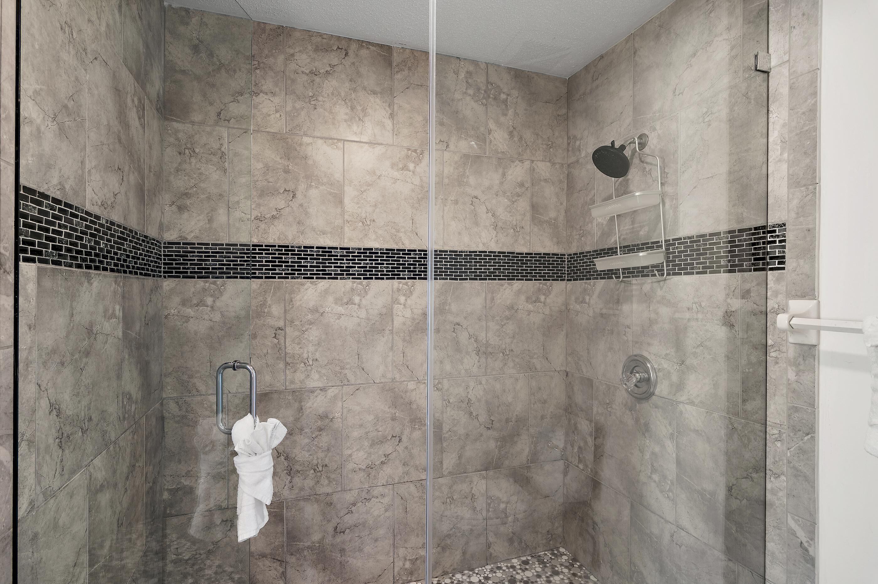 A shower area with a glass door, a towel rack, and a showerhead.