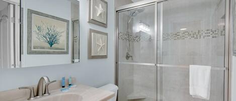 Une salle de bain avec un grand lavabo, des toilettes et une douche fermée par une paroi de verre.
