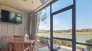 Une chambre dotée d’une grande fenêtre donnant sur un terrain de golf, de meubles en bois et d’un téléviseur à écran plat fixé au mur.