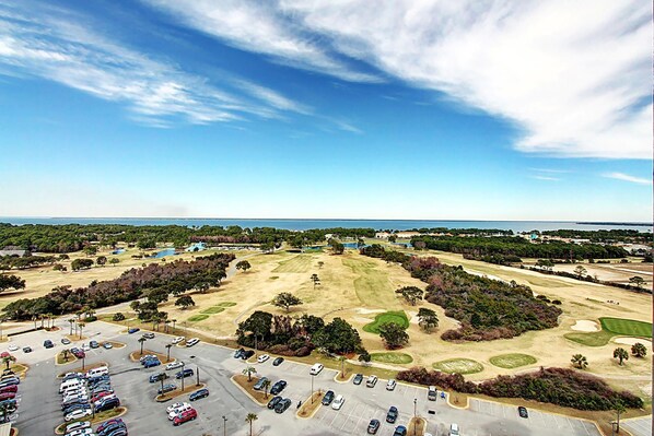 Un terrain de golf doté d’un parking et offrant une vue sur l’océan.
