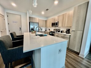 A modern kitchen with a central island, stainless steel appliances, and wooden cabinetry.