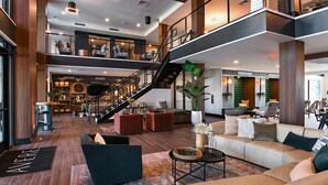 A spacious lobby with a staircase, seating areas, and a reception desk.