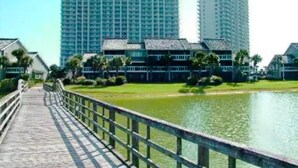 A waterfront hotel with a long wooden walkway leading to the buildings. - Seascape 38A (Miramar Beach)