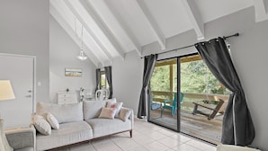Een moderne woonkamer met een grijze bank, een kleine tafel en een grote schuifglazen deur die leidt naar een terras.