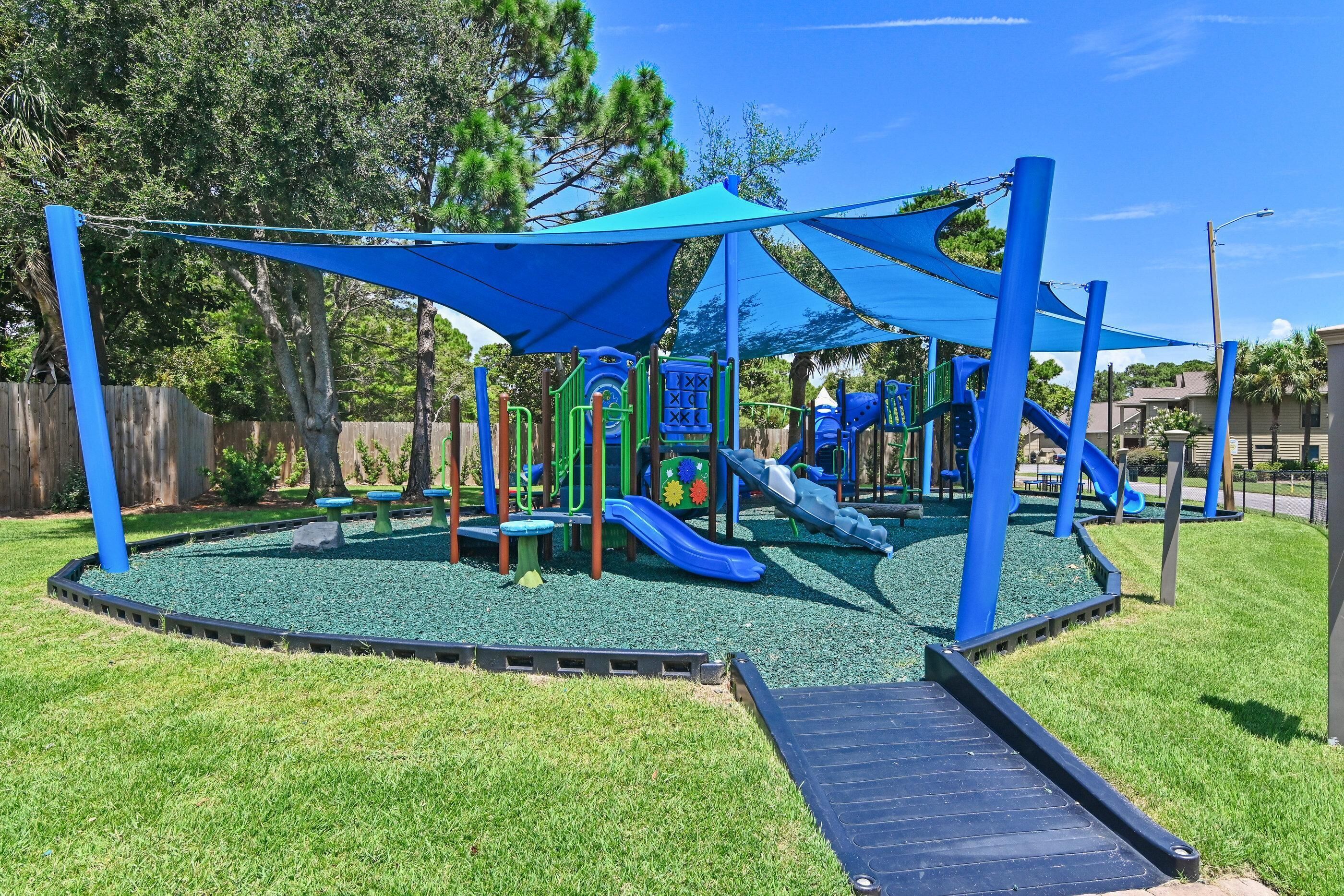 Ein Spielplatz mit Rutschen und Klettergerüsten, umgeben von einem eingezäunten Rasenbereich.