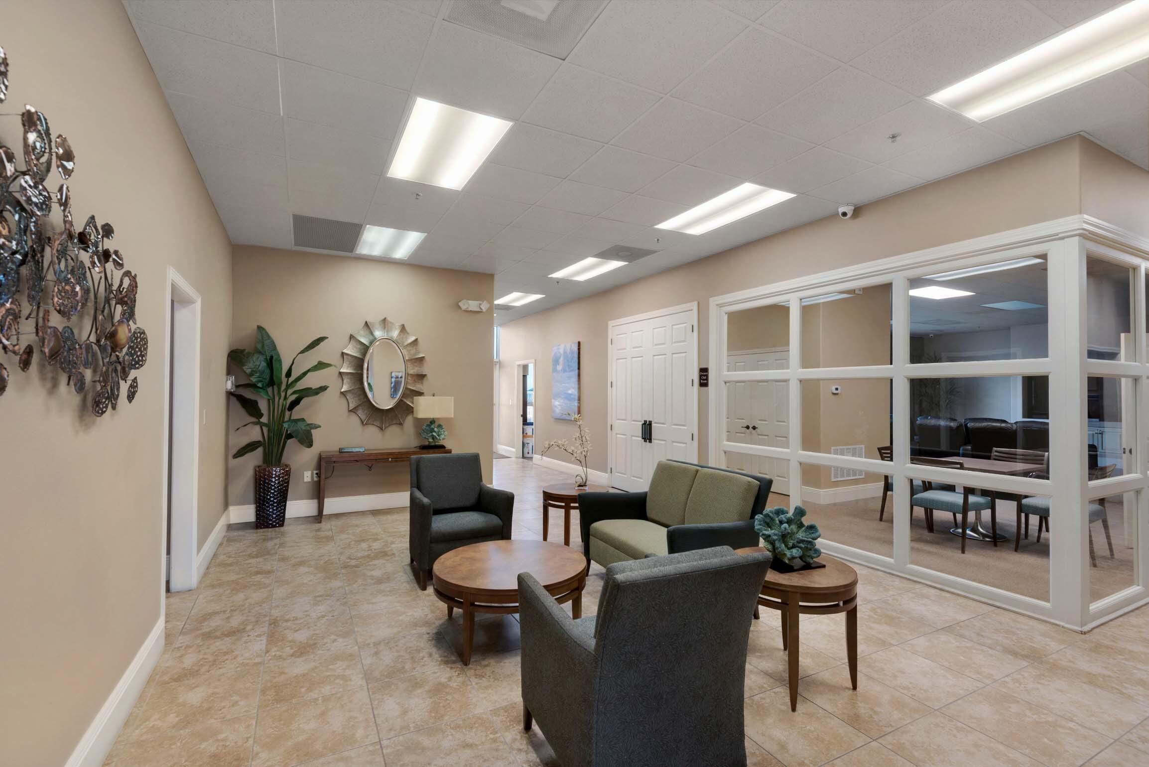 A spacious lobby with a seating area, a large mirror, and a view into a dining area.