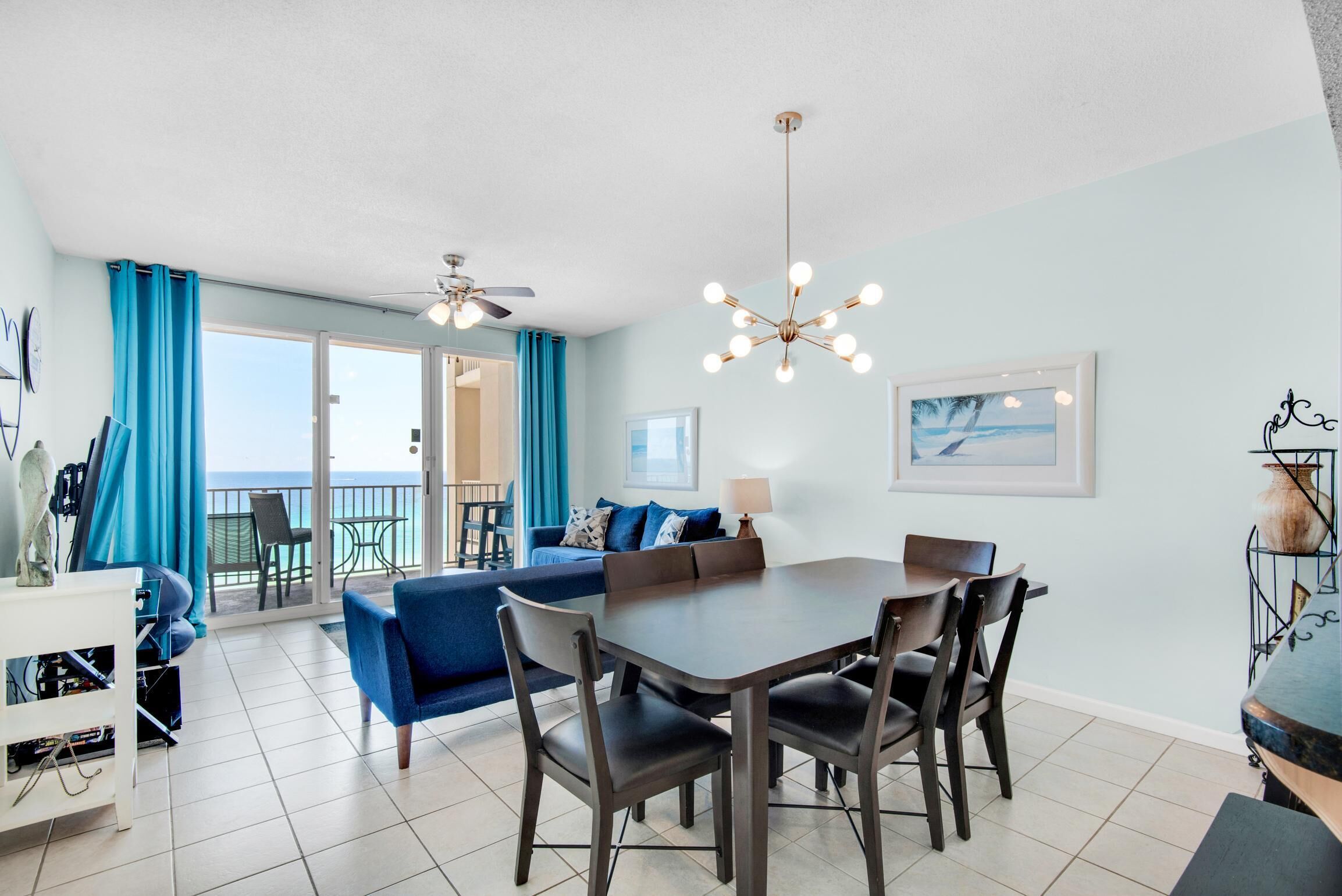 A modern living room with a dining area, a ceiling fan, and a view to the outside.