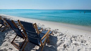 A beach with rows of blue lounge chairs and a clear view of the ocean.