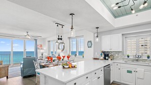 A spacious kitchen with a large island, white cabinetry, and a view of the ocean.