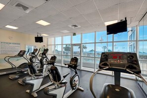 A fitness center with treadmills, a TV, and large windows. - Majestic Sun 1012a (Miramar Beach)