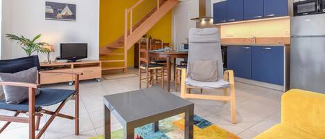A modern apartment with a living room, dining area, kitchen, and a staircase.