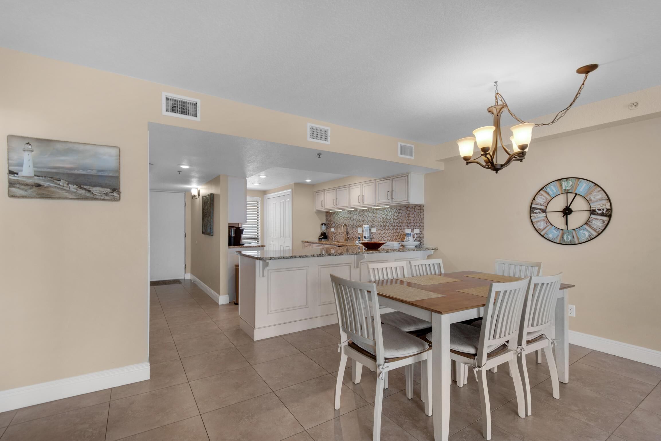 A spacious kitchen with a central island, white cabinetry, and a dining area with a wooden table and chairs.