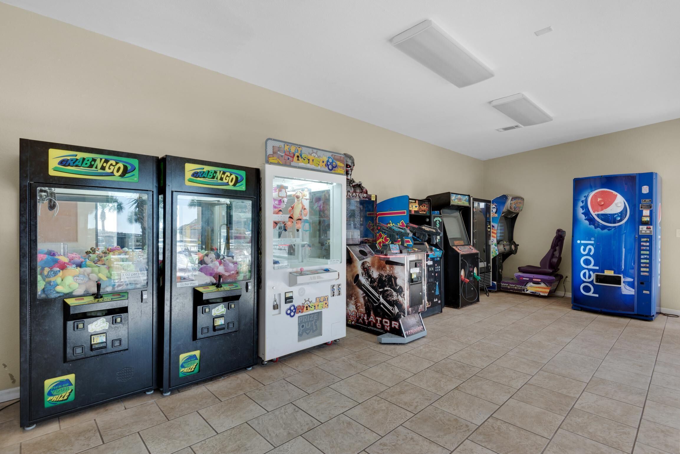 A row of vending machines, including a Pepsi dispenser, in a room with tiled flooring and a plain wall.