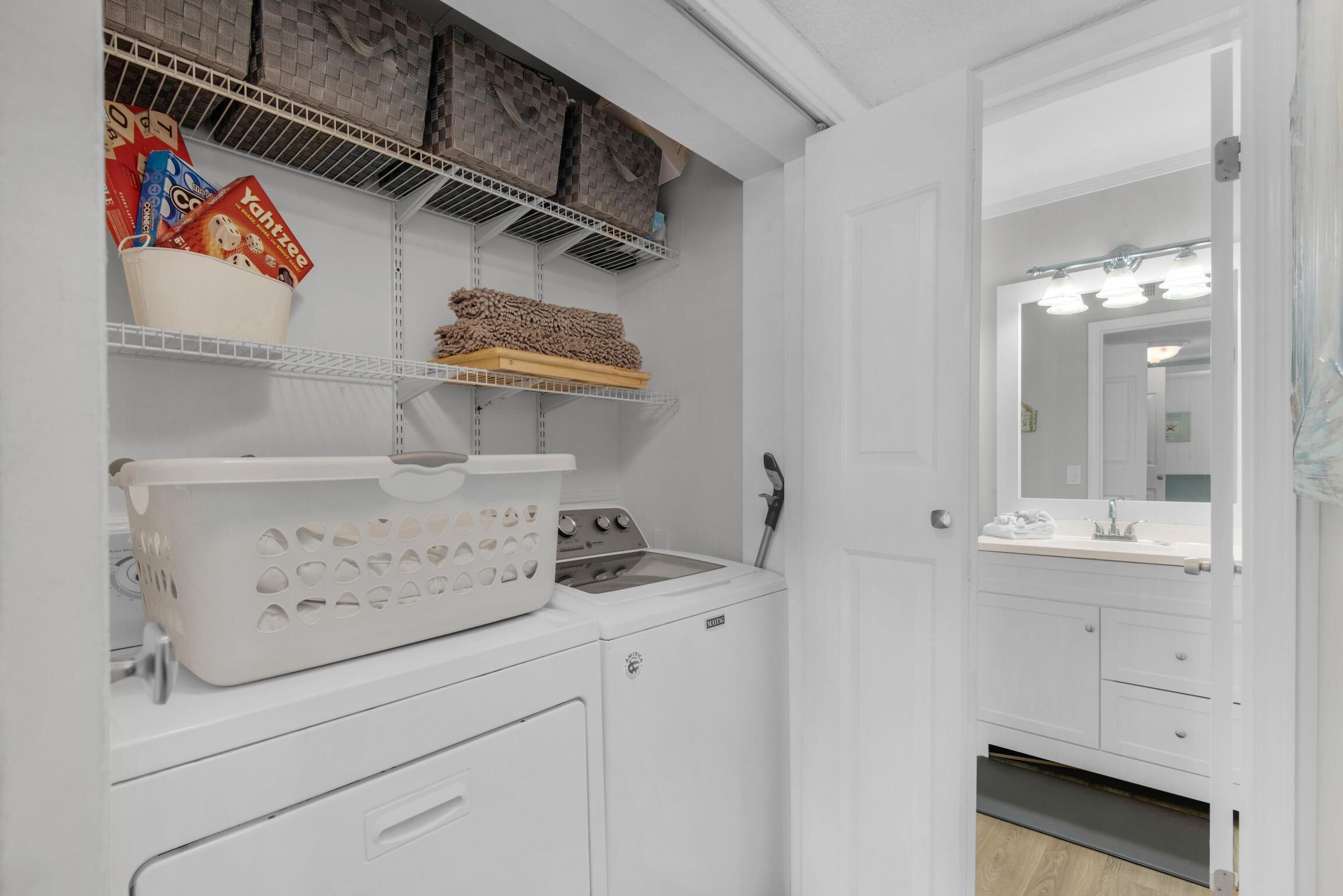 A laundry area with a washing machine, dryer, and shelves with bags and boxes.