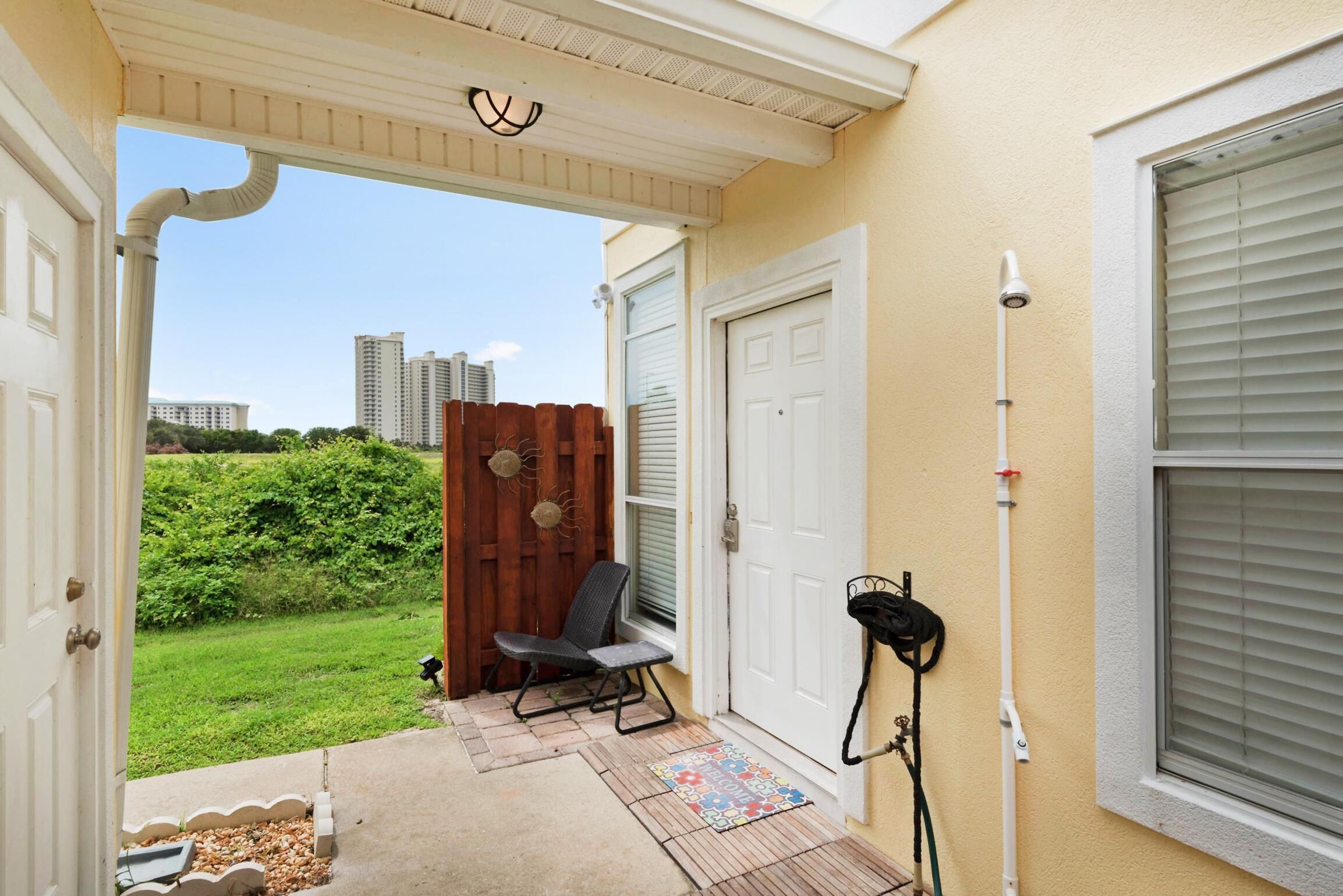 A covered porch with a chair, a door, and a window with blinds.