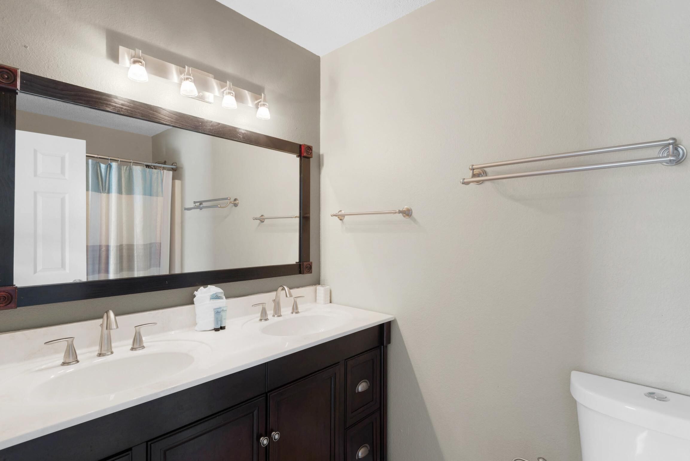 A bathroom with a white sink, dark cabinets, a large mirror, and a towel rack.