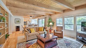 A spacious living room with a wooden ceiling, a sofa, a coffee table, and a TV. - NEW Winter Retreat 4B Hot Tub Sauna Pets Welcome with Tranquil Creek in Backyard (Auburn)