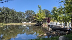 A tranquil outdoor setting with a pond, a wooden deck, and a gazebo. - NEW Winter Retreat 4B Hot Tub Sauna Pets Welcome with Tranquil Creek in Backyard (Auburn)