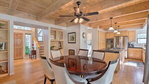 A spacious kitchen with wooden cabinets, a central island, and a dining area with a round table and chairs. - NEW Winter Retreat 4B Hot Tub Sauna Pets Welcome with Tranquil Creek in Backyard (Auburn)