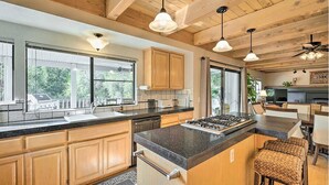 A spacious kitchen with wooden cabinets, a large island, and pendant lighting. - NEW Winter Retreat 4B Hot Tub Sauna Pets Welcome with Tranquil Creek in Backyard (Auburn)