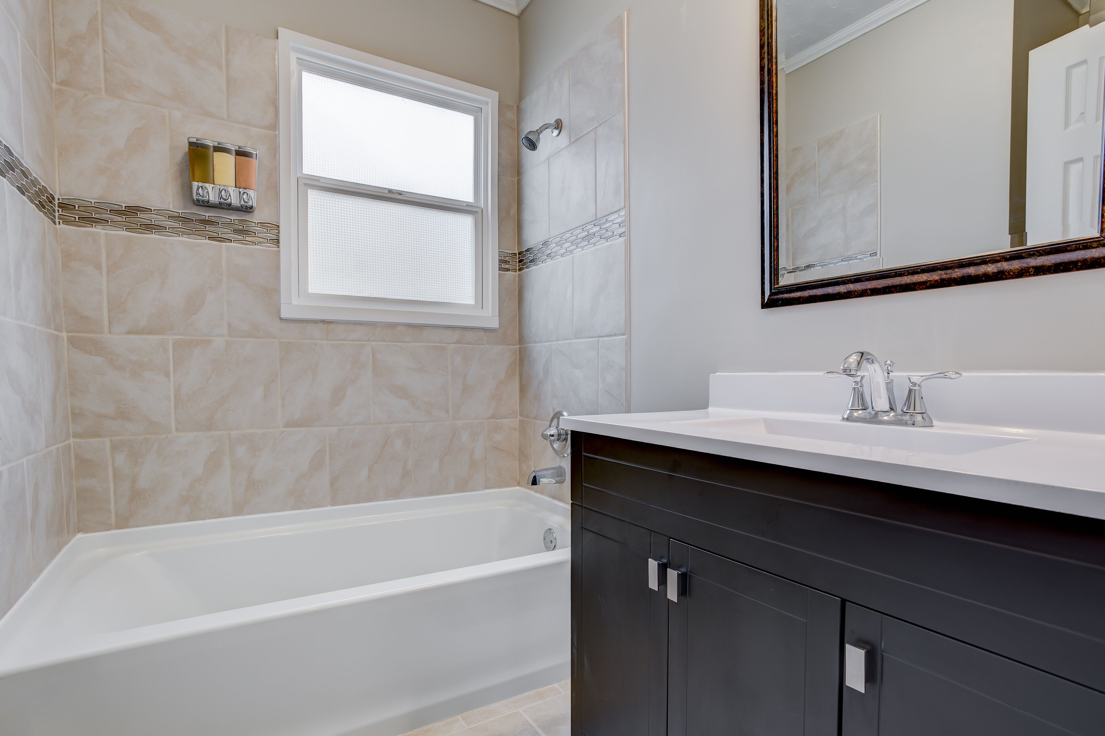 Une salle de bain moderne avec une baignoire, un grand miroir et un meuble-lavabo.