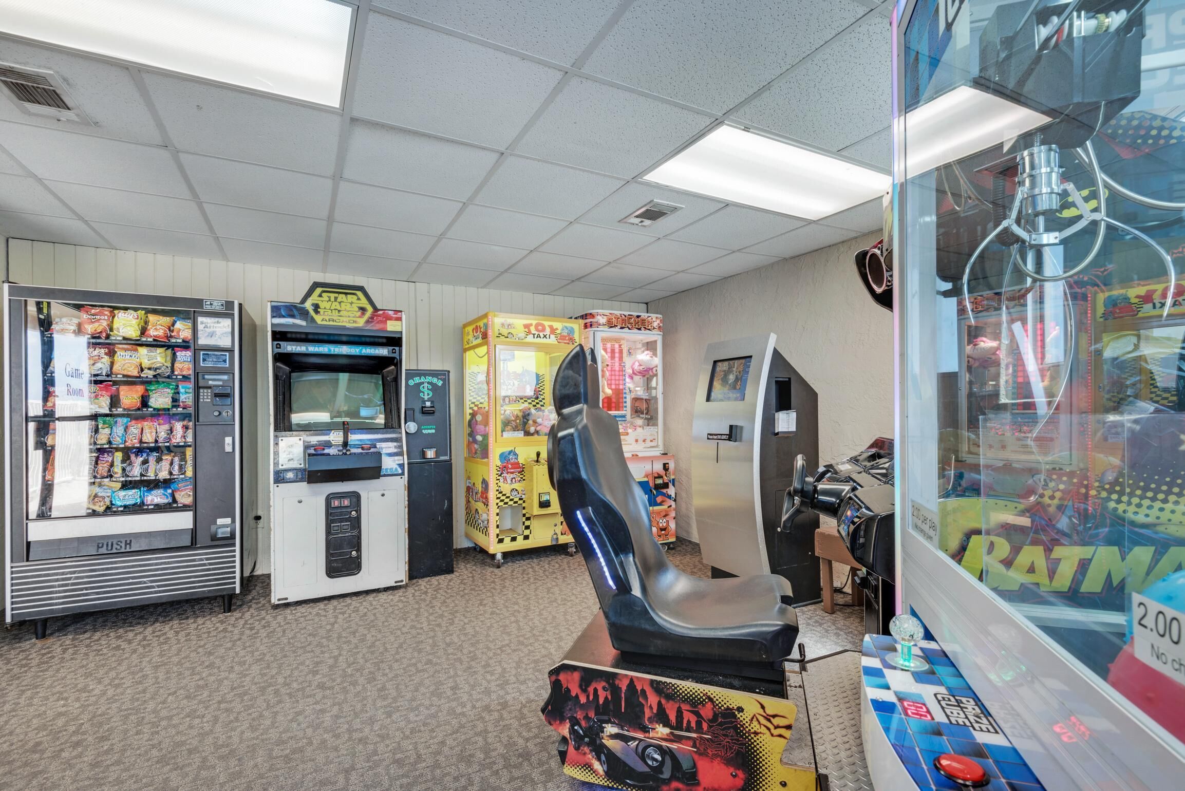 Un'area giochi con cabinati arcade, una macchina a grinfie e un gioco di corse.