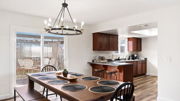Une cuisine moderne avec des meubles en bois, un îlot central et un coin repas comprenant une grande table et des chaises en bois.