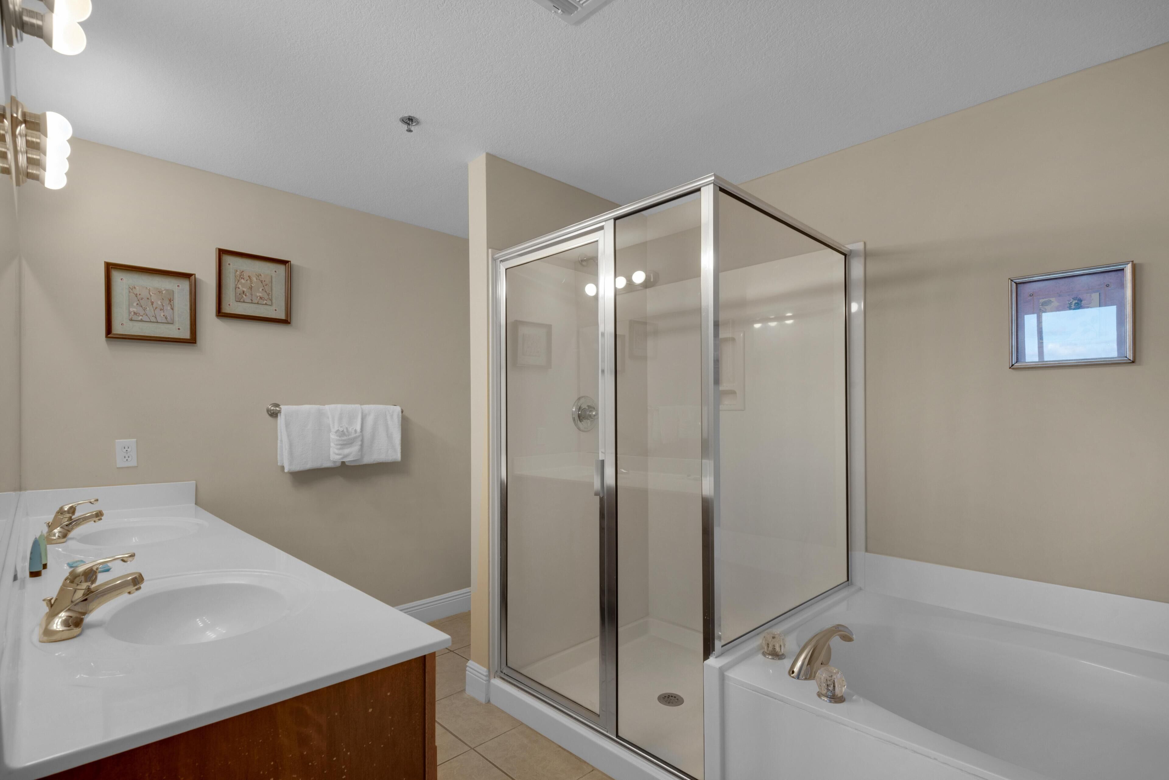 Une salle de bain avec deux lavabos, un espace douche et une grande baignoire.