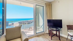 A balcony with a view of the ocean, a sofa, a TV on a glass table, and a chair. - Ariel Dunes II 2006 (Miramar Beach)