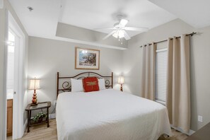 A bedroom with a bed, two bedside lamps, a ceiling fan, a framed picture on the wall, and a window with curtains. - Ariel Dunes II 2006 (Miramar Beach)