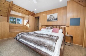 A bedroom with a bed, a window, a wooden ceiling, and a wall-mounted picture. - Big Bear Treehouse-HOT TUB-Gorgeous Views (Big Bear Lake)