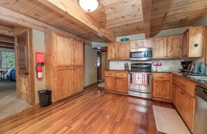 A wooden-paneled kitchen with a stainless steel oven, microwave, and sink. - Big Bear Treehouse-HOT TUB-Gorgeous Views (Big Bear Lake)