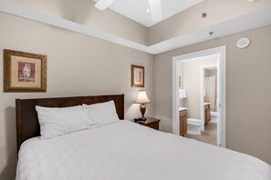 A neatly made bed with white linens, a wooden headboard, and two framed pictures on the wall. - Ariel Dunes II 1805 (Miramar Beach)