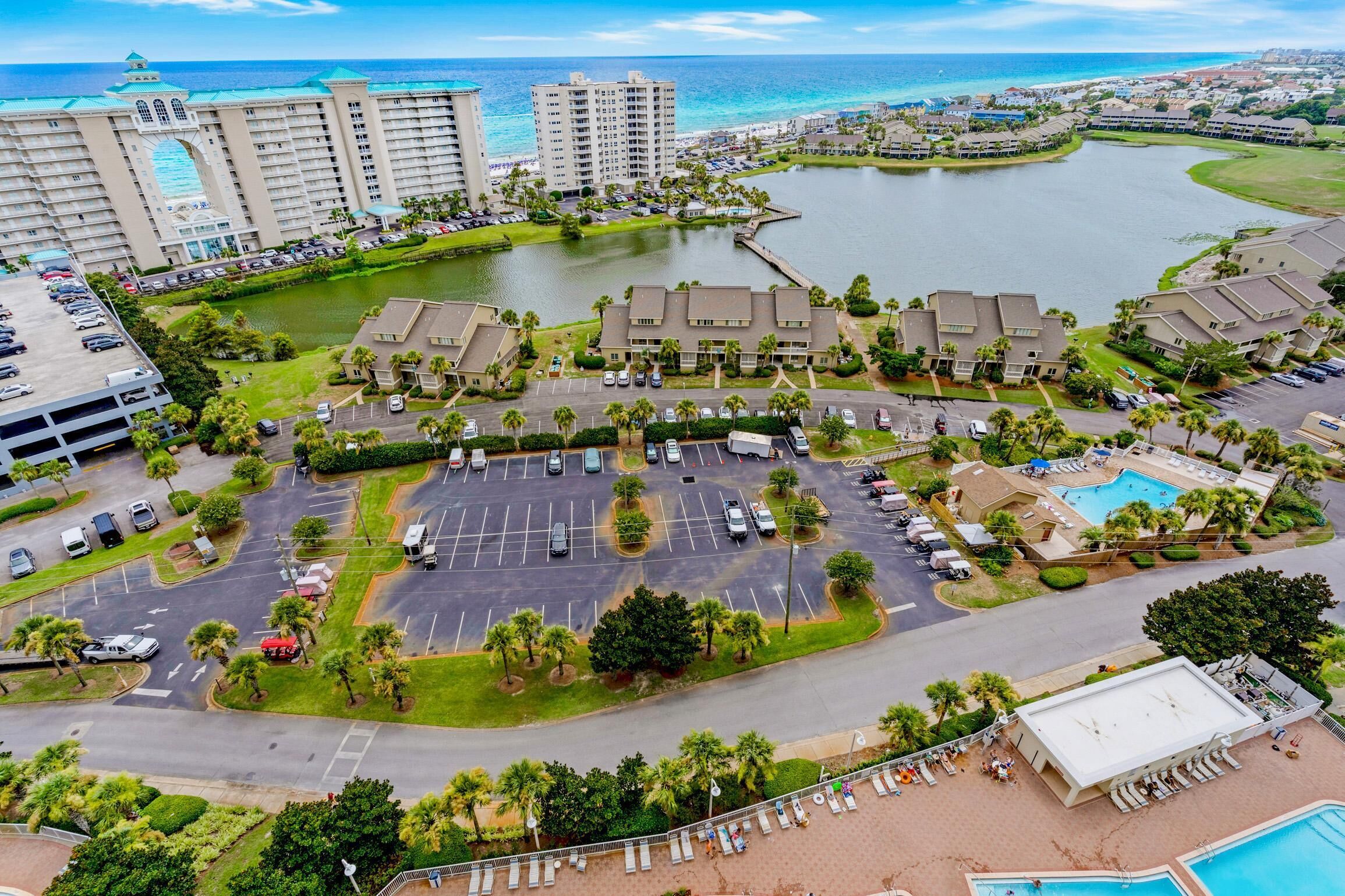 A hotel complex with multiple buildings, a parking lot, and a beachfront pool area.