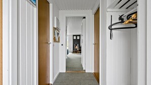 A hallway with white walls, a wooden door, and a carpeted floor leading to a room with a fireplace. - 3 bedroom awesome home in Ulfborg (Ulfborg)