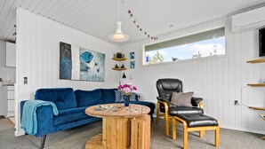A modern living room with a blue sofa, a wooden coffee table, and a black leather chair. - 3 bedroom awesome home in Ulfborg (Ulfborg)