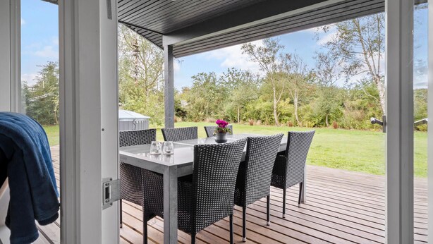 An outdoor patio with a table and chairs, a potted plant, and a view of a grassy area with trees. - 3 bedroom awesome home in Ulfborg (Ulfborg)