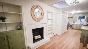 A modern kitchen with white cabinetry, a built-in fireplace, and a round mirror above it. - Spacious, Town Square, Theatre Room! 4 bed / 2 bath Private Home on town square (Covington)
