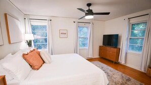 A bedroom with a bed, a television, a ceiling fan, and windows with curtains. - Spacious, Town Square, Theatre Room! 4 bed / 2 bath Private Home on town square (Covington)